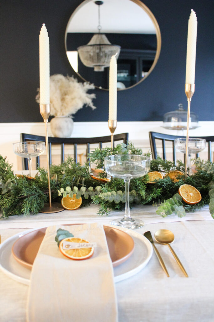 table setting using a faux garland and some real eucalyptus and orange slice name cards