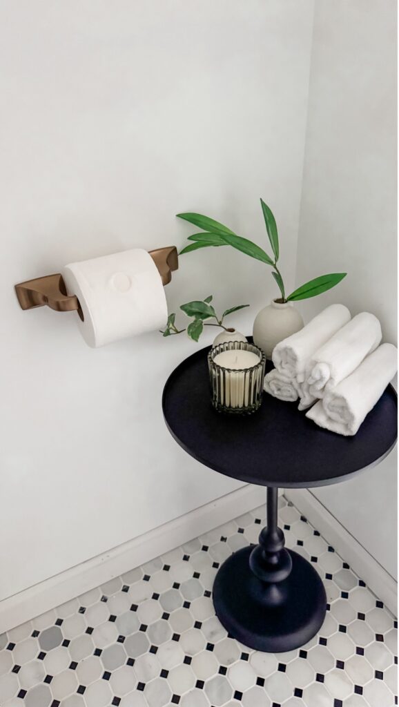 side table with hand towels, tissue holder, candles and bud vase